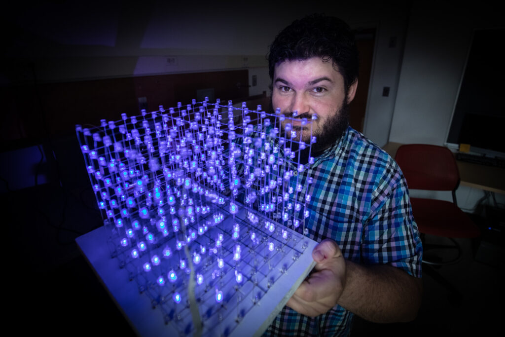 Man showing a glowing 3D cube model