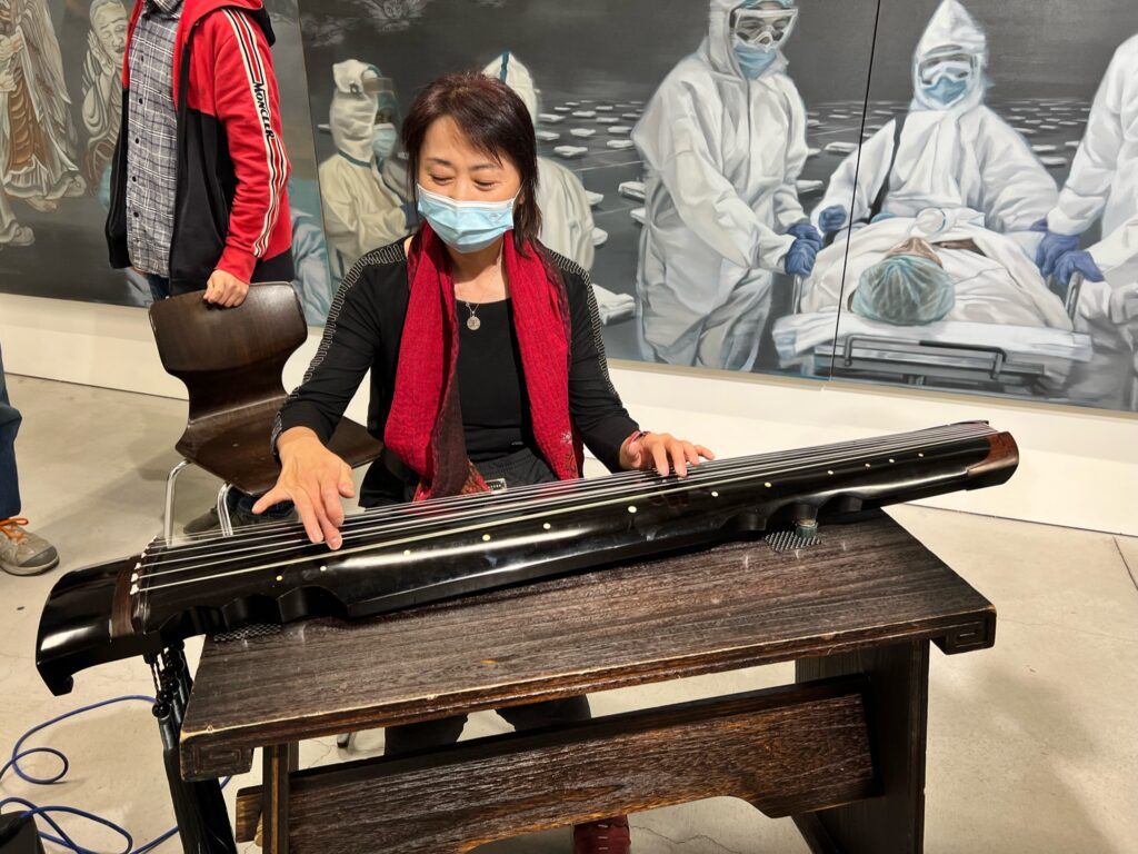 A Woman playing the Chinese goquin at a musical performance and poetry reading, 